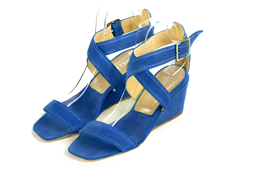 Electric blue elegant sandals with cross straps across the instep, fully open. Square toe. Medium wedge heels.